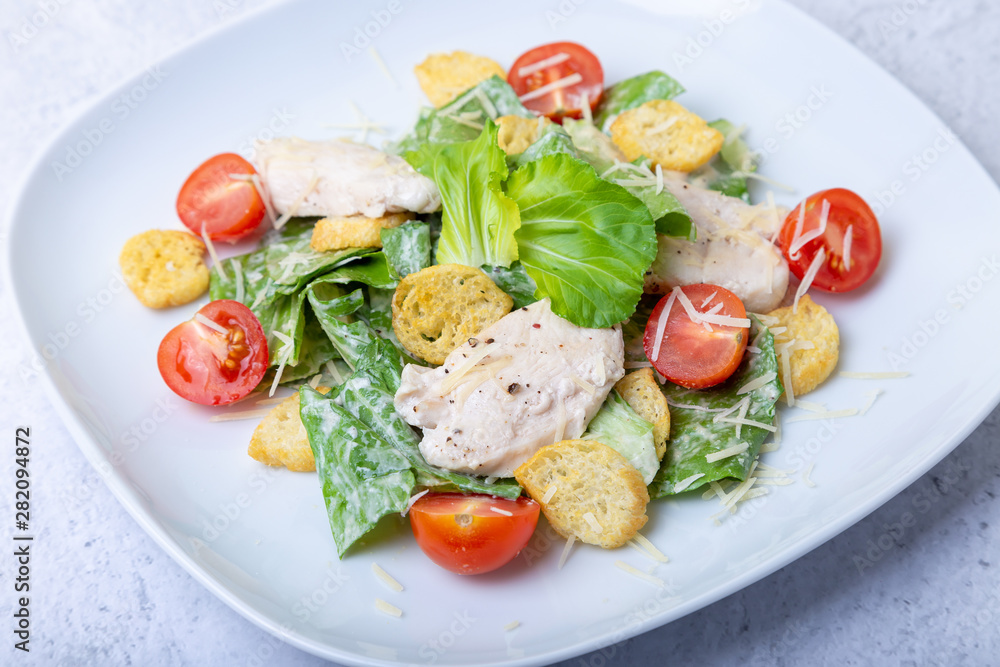 Caesar (cesar) salad with chicken, crackers, parmesan and cherry tomatoes. Close-up. Caesar (cesar) salad with chicken, crackers, parmesan and cherry tomatoes. Close-up.