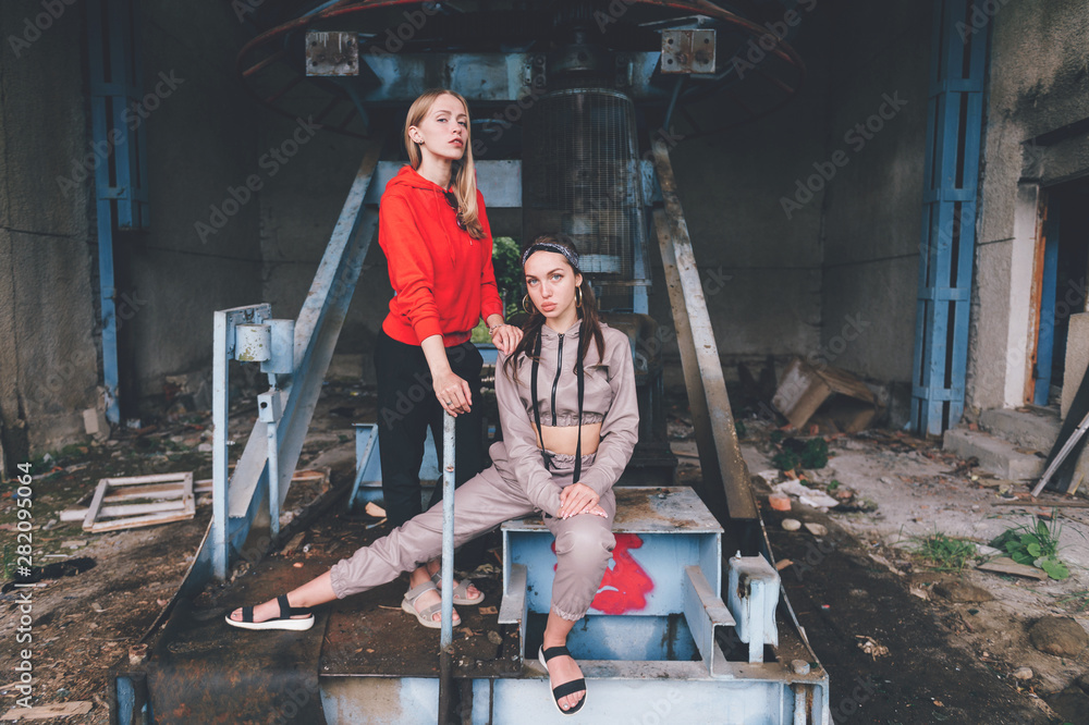 Stylish female couple posing at abandoned cableway station