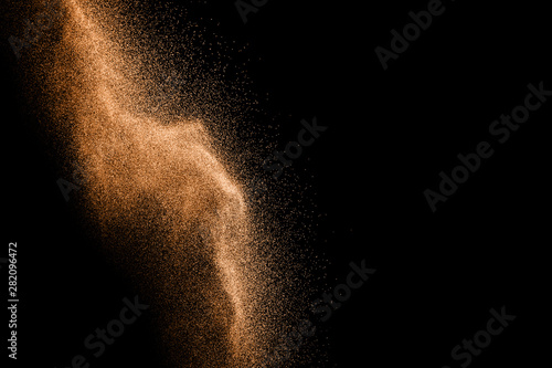 Abstract sand cloud.Brown sand splash against dark background. Brown dust explosion.