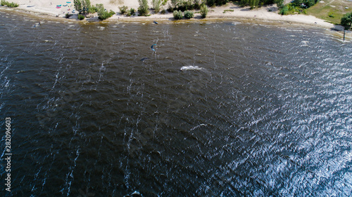 Aerial view of many people who make kitesurfing activity  on beach 