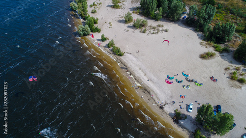 Aerial view of many people who make kitesurfing activity  on beach 
