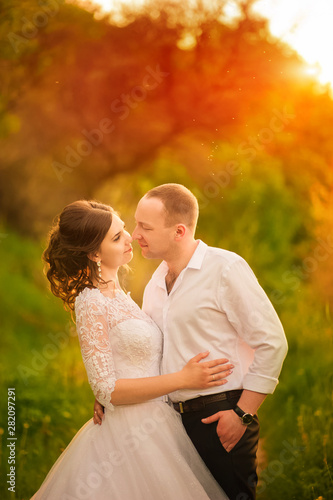 Romantic wedding couple at sunset. Close-up bride and groom in the setting sun and copy space. © Nelly