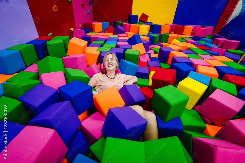 A young woman or girl, mother playing and jumping in soft cubes in the dry  pool