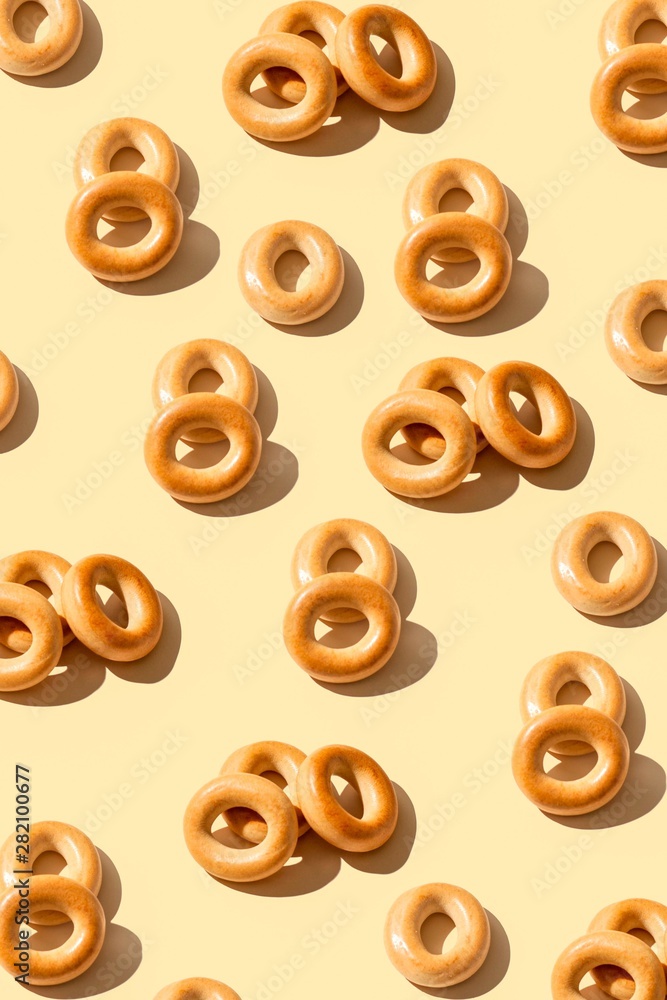 Fototapeta premium Bagels pattern on a peach color background . Bakery product template, traditional Russian bread product. Creative layout. Top view
