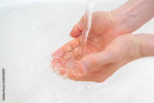 person’s hands washing with pouring water in bathroom