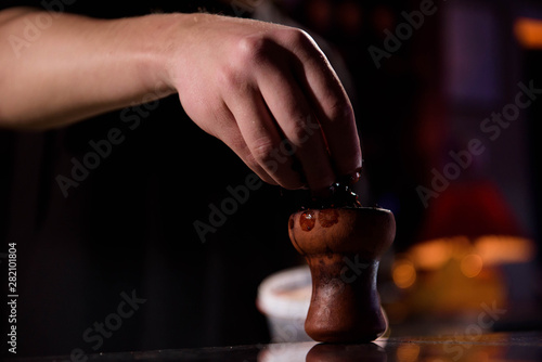 Barman fills black burnt ceramic bowl for hookah smoking different types of tobacco.