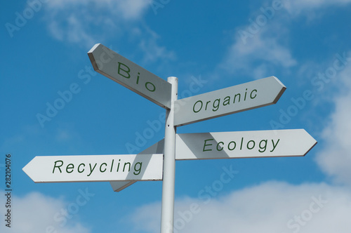 Closeup of direction panels with different ecological choices on cloudy sky background