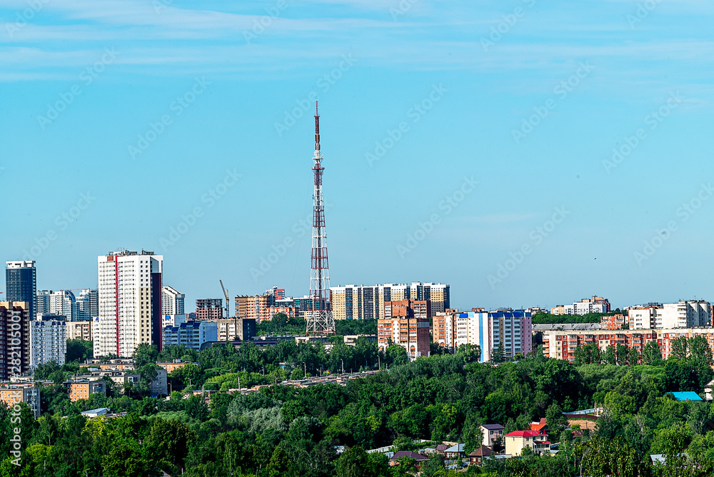 Fototapeta premium In the center of the image is an old television center. To the right and left of it are high-rise buildings. In the foreground trees, one of the streets. Early morning, June.