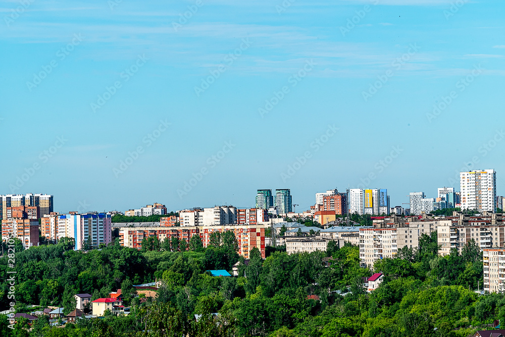 In the foreground one-storey buildings and trees. In the background, high-rise buildings. This is the outskirts of Perm. June, early morning, cloudless sky.