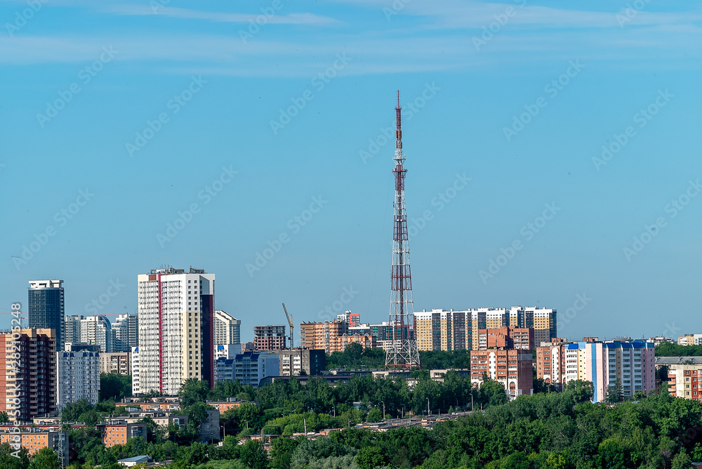 Before us is the old TV tower and the surrounding high-rise buildings. In the foreground one-storey houses on the outskirts of the city of Perm. Early June morning.