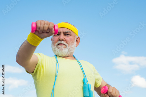 Senior male is enjoying sporty lifestyle. Elderly man practicing sports on blue sky background. Elderly man after her workout. Senior man in health club.