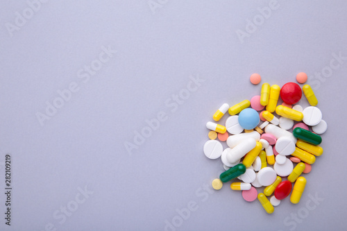 Colored pills and tablets on a grey background, top view