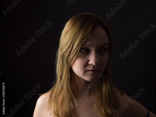 portrait of young woman, no make up, low key, brown dark hair, natural looking making expressions 