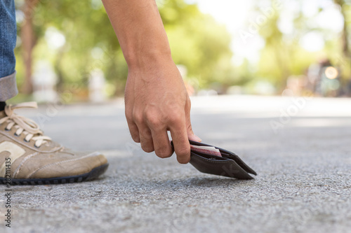 Asian man picking black wallet on the road in tourist attraction