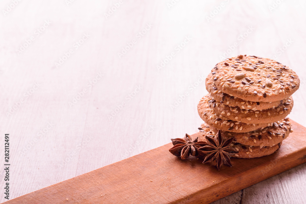 Fototapeta premium Cookies of sesame seeds, sunflower seeds and other spices on a wooden plate. Bright key