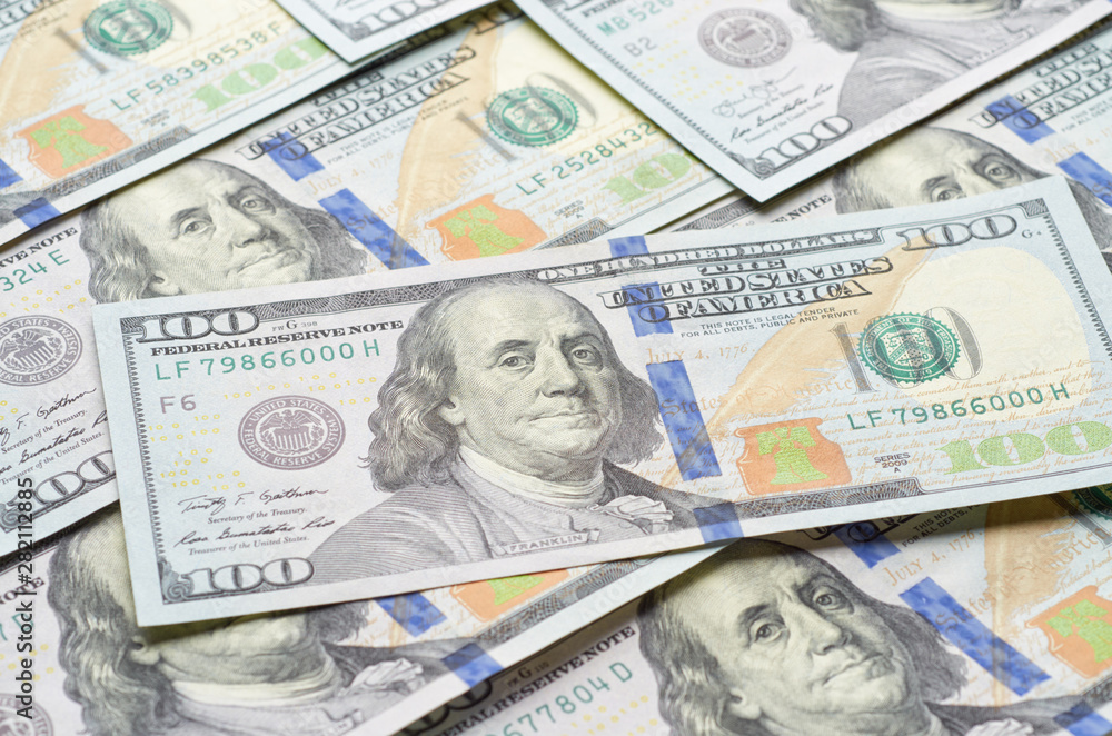 Background from chaotically lying of notes for one hundred dollars. In the foreground, one hundred-dollar bill. Background from chaotically lying of notes for one hundred dollars. In the foreground, one hundred-dollar bill.