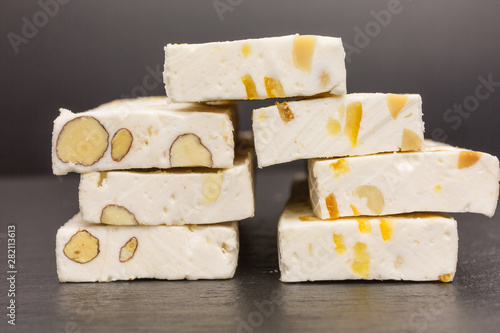 stack of white nougat with peanuts and orange peel and almonds