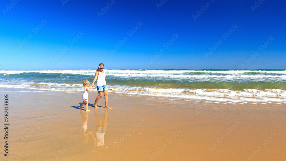 Happy mother and daughter spend their holidays on the seashore.