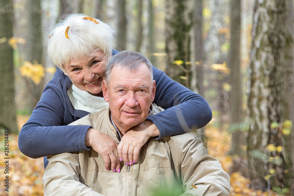 Happy senior couple sitting and smiling in an autumn park