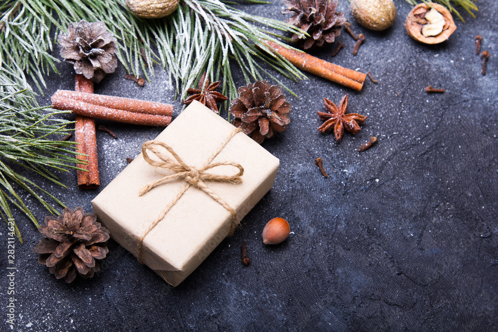 Christmas background with decorations. Christmas presents, pine twigs and cones covered with snow on dark background Christmas background with decorations. Christmas presents, pine twigs and cones covered with snow on dark background