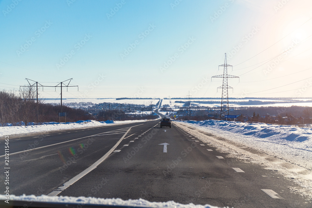 Winter road on the background of the sun in blue sky