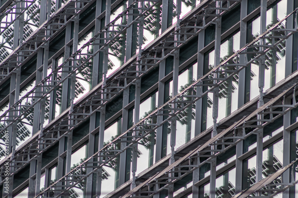 Moderne Glasfassade eines neuen Bürokomplexes erhält energieeffizienten Sonnenschutz mit Solarzellen zur optimalen Stromgewinnung und Umweltschutz Moderne Glasfassade eines neuen Bürokomplexes erhält energieeffizienten Sonnenschutz mit Solarzellen zur optimalen Stromgewinnung und Umweltschutz