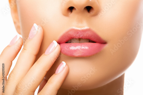 Close up beautiful  Lips. Beauty Fashion woman lips with natural Makeup. shine lipstick. isolated. Closeup mouth Nude Colors lacquered model touches her lips with her hand. Make up. 