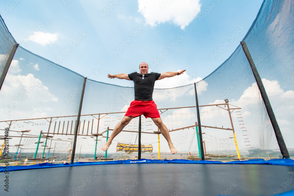 The boy jumps on a trampoline in an amusement park, performing various  stunts. Stock Photo | Adobe Stock