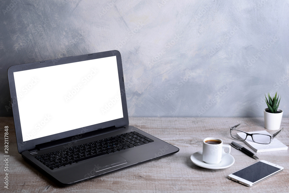 Fototapeta premium Laptop with blank screen for graphic display montage .Computer on wooden gray desk in office room. Mock up with plastic plant