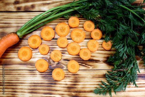 Fresh crop of carrots with tops and sliced in circles lies on the table