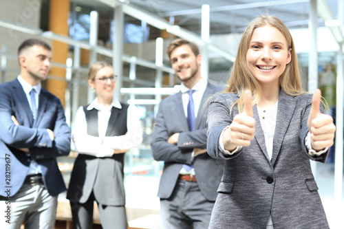 business concept - attractive businesswoman with team in office showing thumbs up.