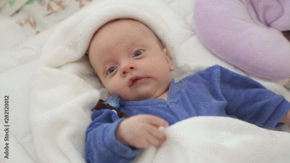 baby boy in a blue bodysuit is lying in his crib. next to the baby pillow for babies and nipple baby boy in a blue bodysuit is lying in his crib. next to the baby pillow for babies and nipple