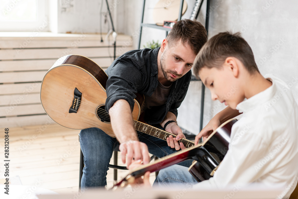 custom made wallpaper toronto digitalTwo brother playing guitar. Older brother teaches younger one to play chords correctly