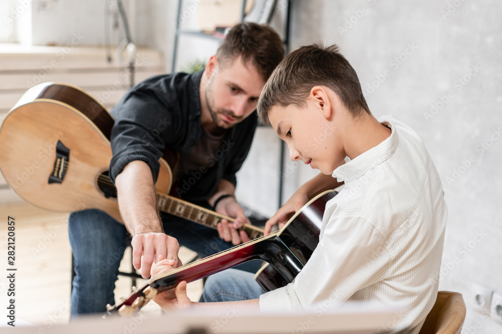 custom made wallpaper toronto digitalAdult man explains his son, who learn to play guitar, how to play studied chord correctly. Education with family