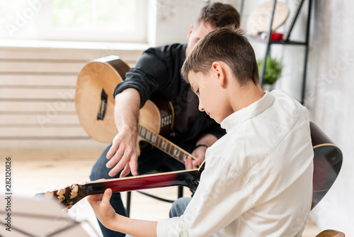 A personal tutor explains to his young student how to play studied chord correctly. Musical education at home