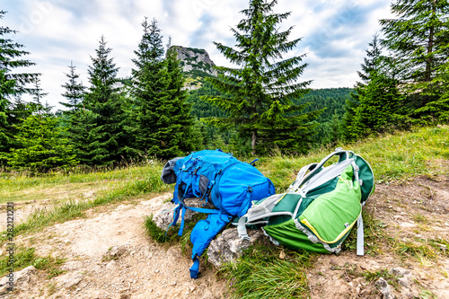 Tourist bagpack and krosna placed on the meadow near Maly Rozsutec mountain in Mala Fatra national park. Green and blue bags used by tourist for outdoor and touristic activities.