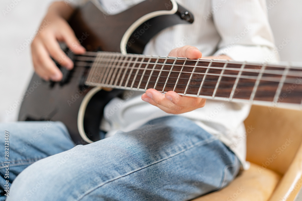 Closeup of electric guitar in hands of young boy in casual clothes