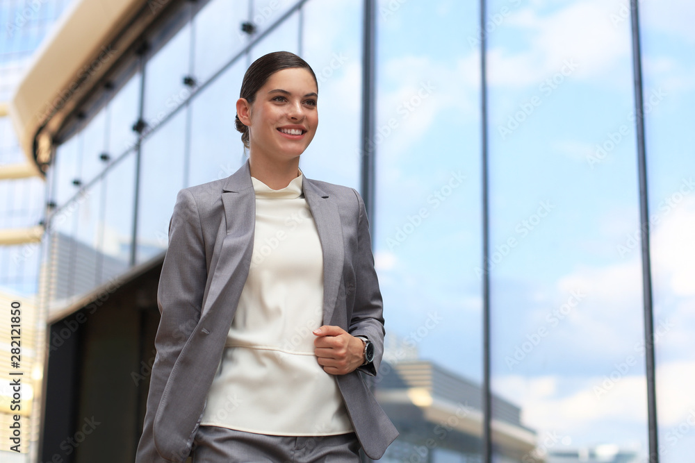 Portrait of successful business woman in suit looking away while walking outdoors. Portrait of successful business woman in suit looking away while walking outdoors.