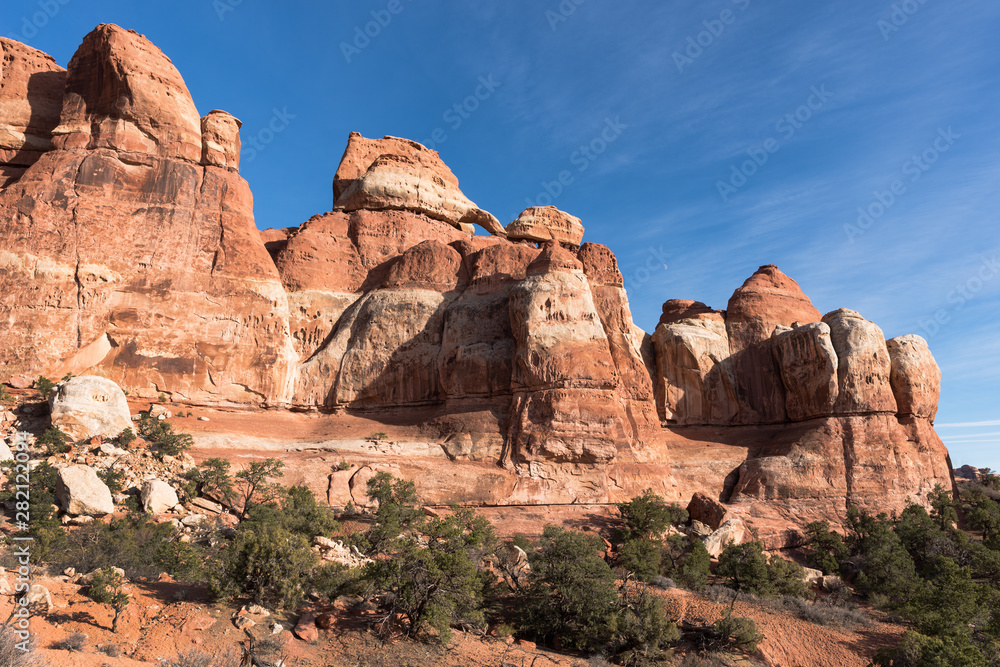 Chesler Park is located within the Needles District of Canyonlands National Park, Utah. A small arch and moon adds to the drama of the pinnacles in the desert landscape. 