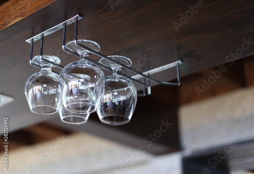 Glass goblets in interior wood alcoholic bar. © Liliia