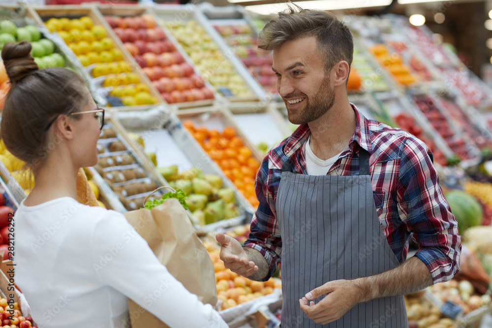 Waist up portrait of handsome young man talking to customer while working in supermarket, copy space