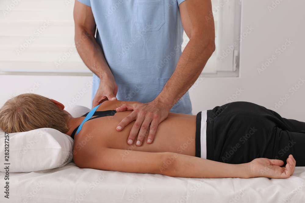 Obraz premium Boy having chiropractic back adjustment. Osteopathy, Physiotherapy and Kinesiology for children. Bad posture correction