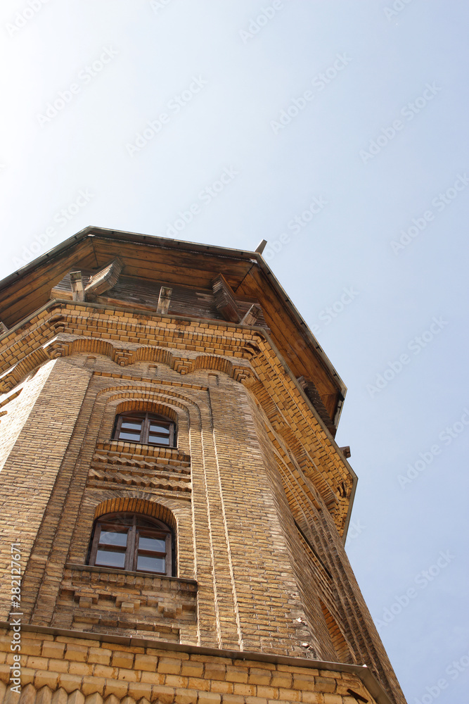 Old water tower building yellow brick wall European architecture tower top on blue sky background