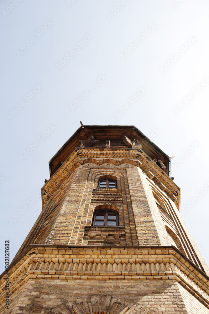 Old water tower building yellow brick wall European architecture tower top on sky background