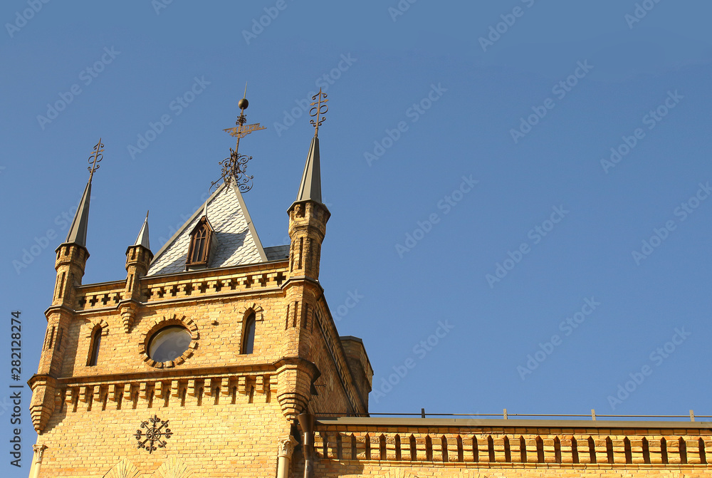 Old gothic castle tower top on blue sky background