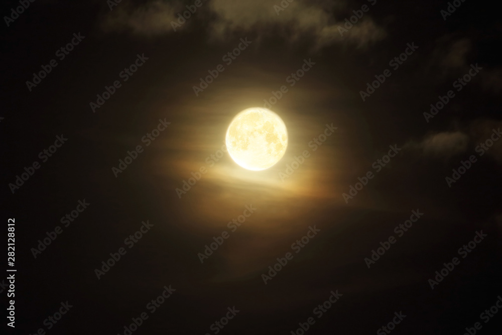 Full moon in clouds on black sky background