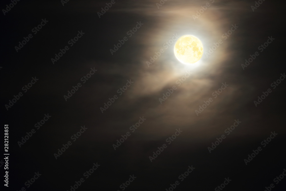 Full moon in clouds on black sky background