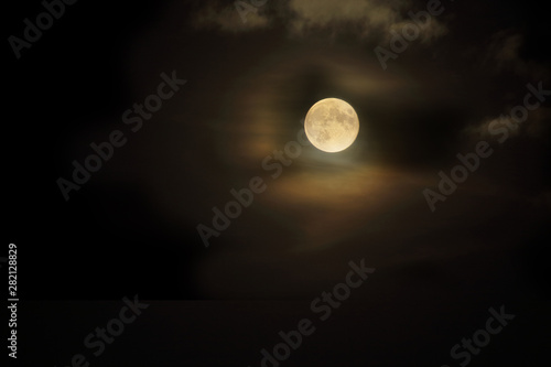 Yellow full moon in dark cloudy sky