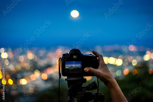 Obraz na plátně Silhouette of the hand taking photo with dslr camera on tripod in the night ligh