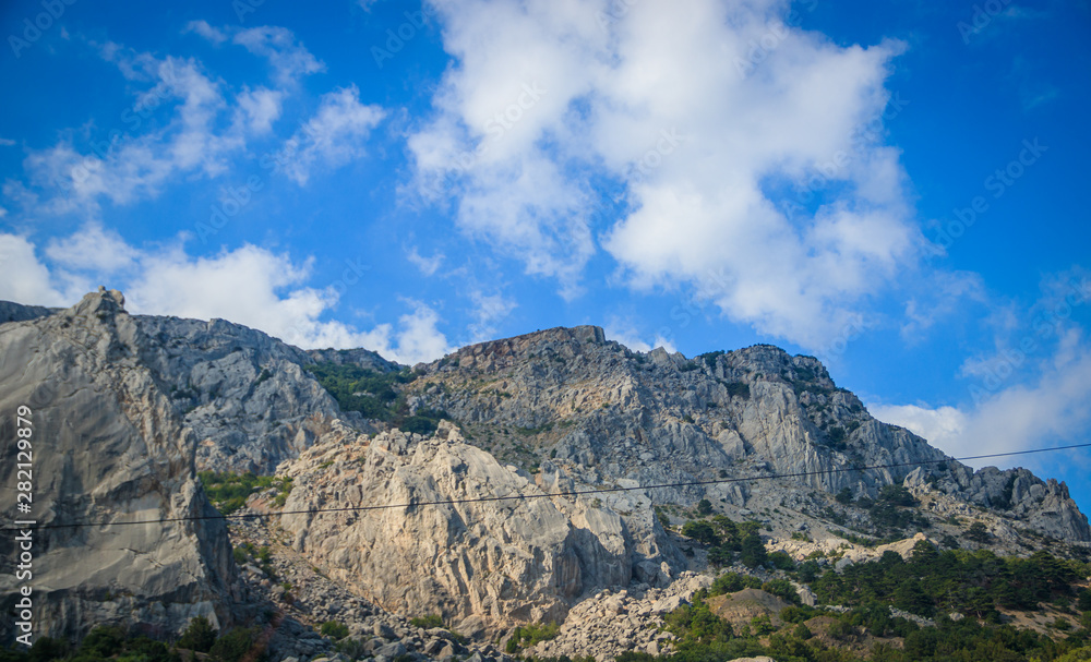 Fototapeta premium Russian mountains. Crimea. Summer mountains background. Forest and mountains in the sun on the background of a cloudy sky above the peninsula of Crimea. Sunny, bright, saturated raster photo